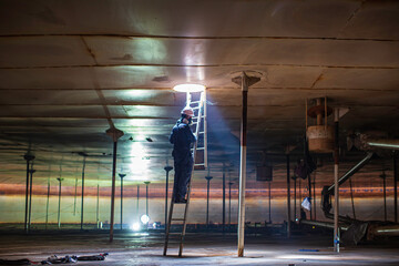 Male worker climb inside the stairway storage visual inspection tank into the confined space