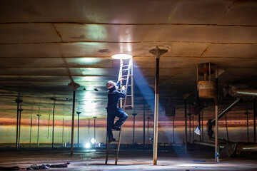 Male worker climb inside the stairway storage visual inspection tank into the confined space