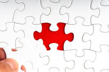 Fototapeta premium Hands holding Red jigsaw puzzle pieces on red background. Copy space and business concept