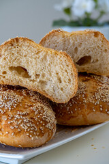 Fresh challah bread rolls hot from the oven cut into half. Crumb shot of gluten free bread buns or mini loaves with sesame seeds and golden color. Fluffy homemade bread, white background with flowers
