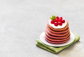 Pink pancakes with cream and fresh berries on a plate on a linen napkin on a light background copy space