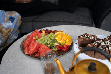 Fototapeta na wymiar Dessert table with fruit, cake and hot beverage