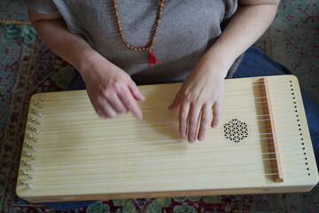 Caucasian woman holding a monochord, sound healing instrument in a therapy session, hands close up.