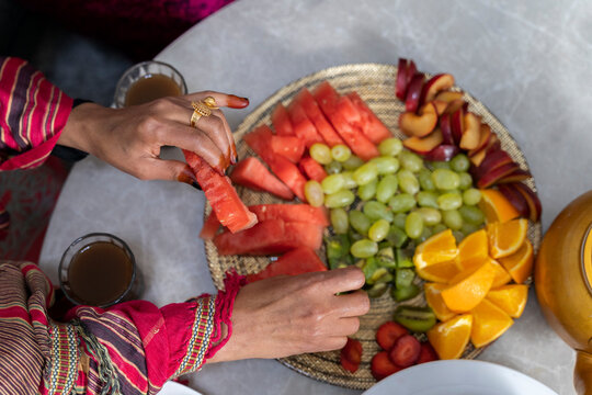 Women with henna on fingers eating fruit from fruit platter