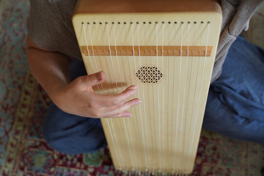 Caucasian woman holding a monochord, sound healing instrument in a therapy session, hands close up.