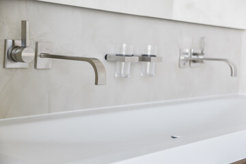 Modern bathroom cabinet with double washbasins and wall mount minimalist faucets and toothbrush cups - Powered by Adobe