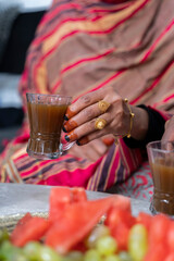 Black Muslim woman holding a cup of coffee with gold jewellery on hand