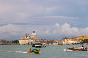 Cathedral of Santa Maria della Salute (Basilica di Santa Maria della Salute). Venice, Italy. Stormy sky, dark clouds, Voparreto and boats sail along the canal.