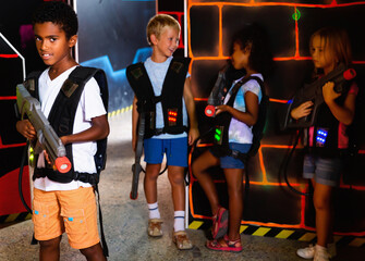 Portrait of happy cheerful preteen boy with laser pistol posing in laser tag labyrinth. High quality photo
