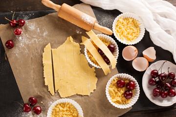 Homemade baking cherry cake ingredients - bowl, flour, eggs and fresh berries on rustic dark table