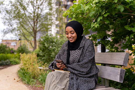 Black Muslim woman on a park bench