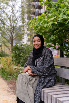 Black Muslim woman on a park bench
