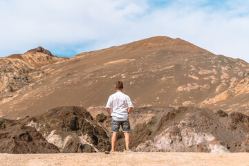 A young man stands on a hill in The Artist's Palette, Death Valley © KseniaJoyg