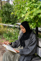 Black Muslim woman on a park bench