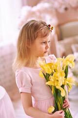 Girl with yellow bouquet of 7 years in pink dress with beautiful hairstyle smiles