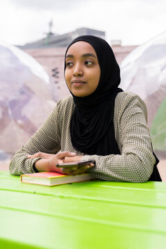 Black Muslim woman on a park bench 