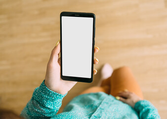 An unrecognizable woman stands and holds a smartphone with one hand. Gadget screen is blank, for...