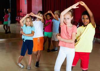Fototapeta premium Smiling happy cheerful positive children primary school trying dancing salsa dance in modern studio