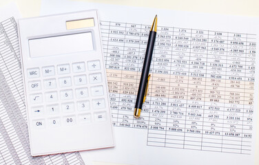 On the desktop is a white calculator, pen and reports. Business concept