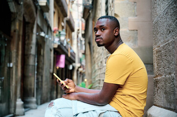 young black woman using smartphone while seated in old town Barcelona