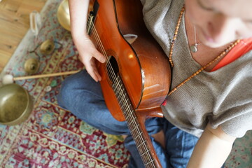 Girl with guitar sitting on the floor in Yogi pose.