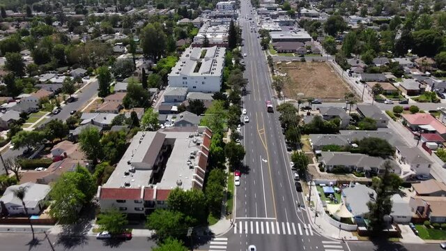Aerial following firetruck, down street in Van Nuys over businesses and homes