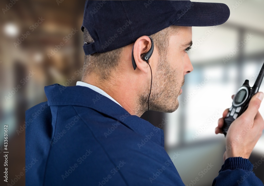 Poster Composition of male security guard using walkie talkie and phone headset over blurred background