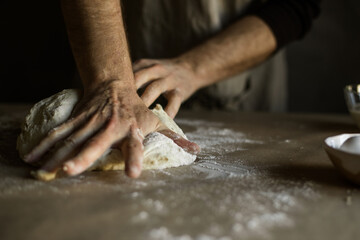Obraz na płótnie Canvas Male hands kneading dough on the table