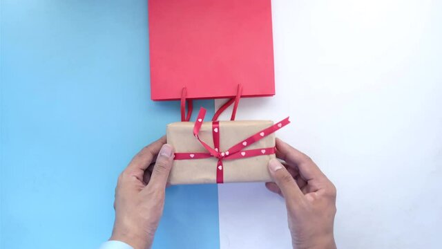 hand in latex gloves wapping a gift box with tissue 