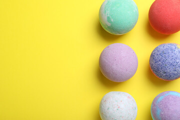 Colorful bath bombs on yellow background, flat lay. Space for text