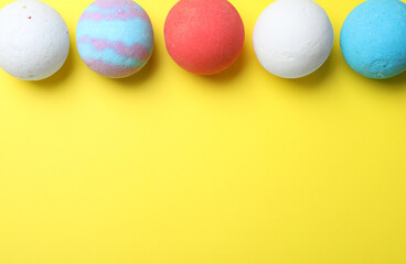 Colorful bath bombs on yellow background, flat lay. Space for text