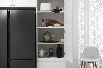 Manual coffee grinder and other appliances on shelving unit in kitchen