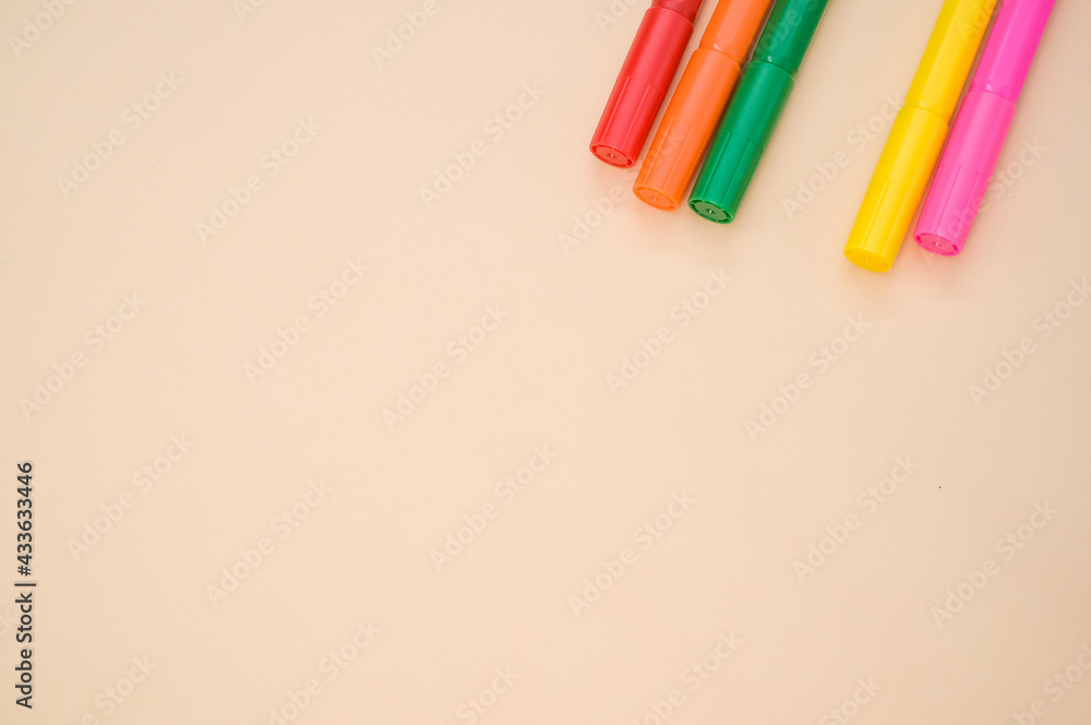 Poster closeup shot of colorful markers isolated on a pink background with space for text
