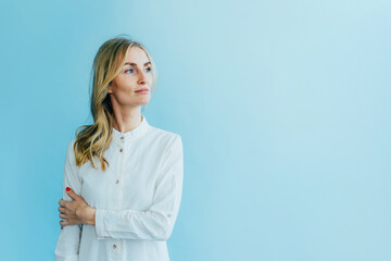 Young fashion white blonde woman in a white dress robe on a blue background.