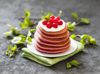 Breakfast, berry pancakes with cream on a plate on a linen napkin on a dark gray background