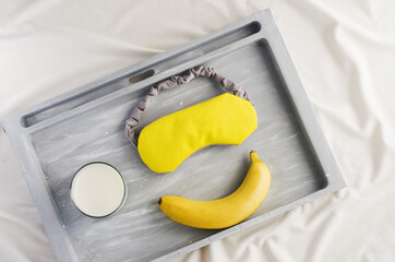 Good sleep foods - banana, milk  and sleep mask. Insomnia treatment. Healthy night sleep. Yellow...