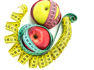 Bright colored measuring tapes twisted in a spiral around a red and yellow apple isolated on a...