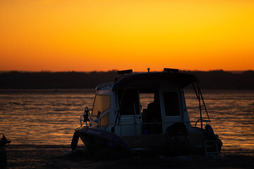 Fototapeta na wymiar Ship on sunset, bright orange sun, big river