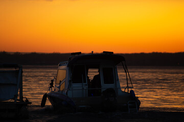 Fototapeta na wymiar Ship on sunset, bright orange sun, big river
