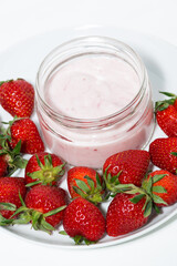 strawberry yogurt in glass jar and fresh berries on white background, vertical top view