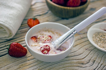 Homemade strawberry face mask. DIY natural home cosmetics mask with oatmeal, cream, strawberries. Authentic wellness cosmetics, natural skin care, non-waste production, sustainable cosmetics