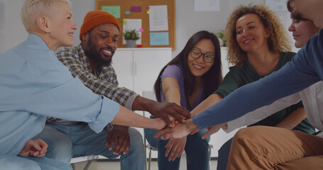 Group of happy multiracial people joining hands at therapy session