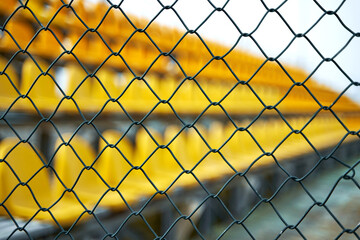 Deserted stands of a small sports field fenced with a net
