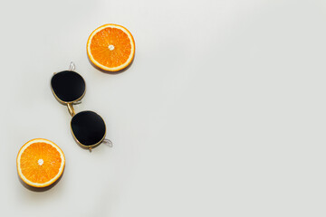 Oranges with sunglasses on a gray background. Citrus summer.