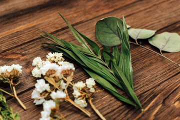 Herbarium. Dry herbs and flowers on a background from wooden boards. Rose, eucalyptus, palm.