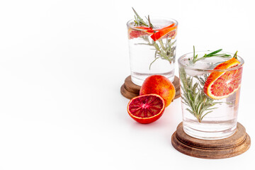 Red orange lemonade in glasses with ice and rosemary
