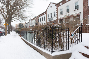 Row of Old Brick Homes along a Snow Covered Sidewalk in Astoria Queens New York during Winter