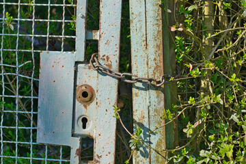 Ein altes, rostiges Metalltor, verschlossen mit einer Kette