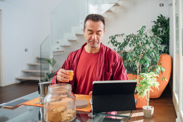 Single adult man relaxing indoor at home using tablet drinking coffee