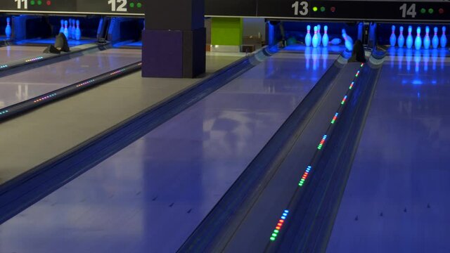 A bowling ball traveling down the lane and knocks down pins.